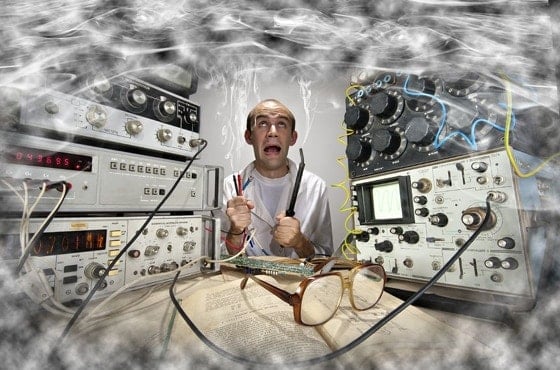 Scientifique affolé entouré de circuits électroniques et appareils de laboratoire en panique
