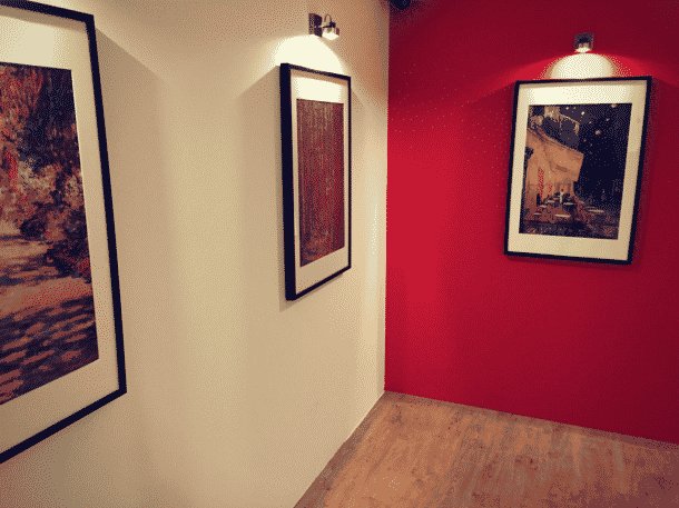 Galerie de musée aux murs rouge et blanc avec cadres et photographies, salle Le Braquage du Musée