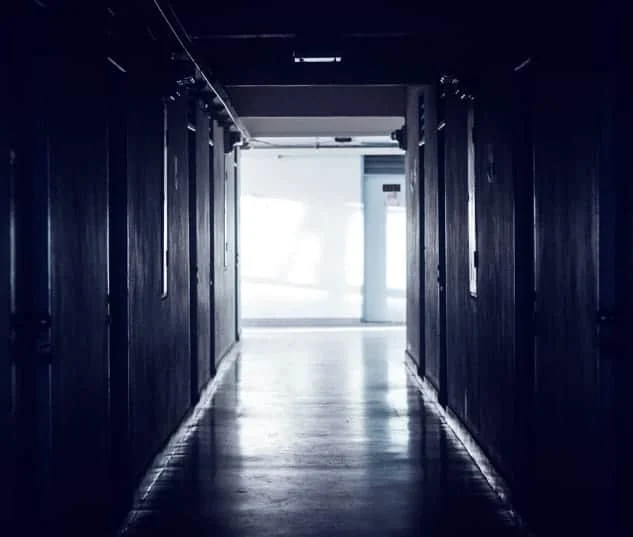 Couloir sombre aux portes grises, lumière blanche au bout, dans L.E H.A.N.G.A.R 3.7
