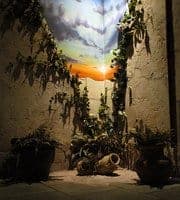 Cour médiévale en ruines avec ciel dramatique orange et lierre grimpant