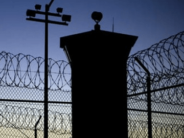 Mirador de prison et barbelés en silhouette sur ciel bleu nuit, salle Prison chez Fox in a Box au Cannet