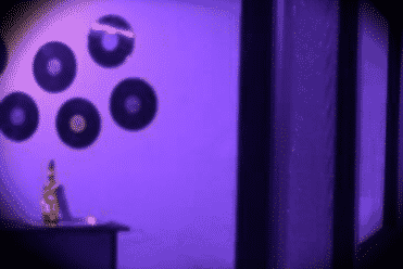 Décor violet avec silhouettes et objets ronds dans la salle Le Réveil du Disco