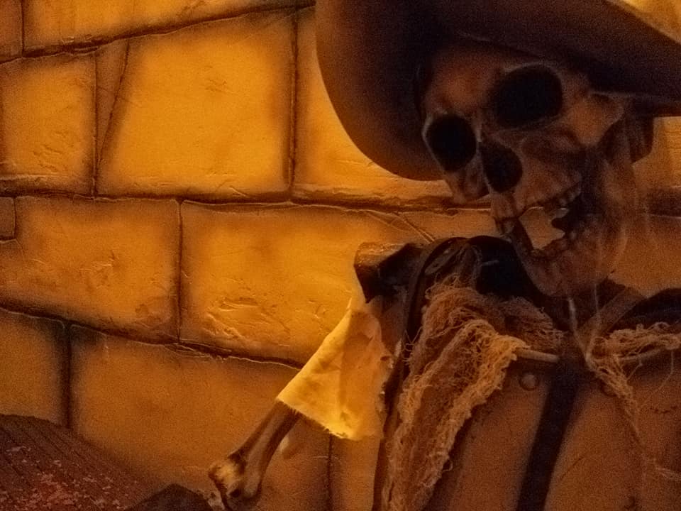 Squelette en costume western contre mur de briques orangées, temple maya chez Aenigma à La Garde