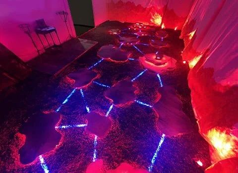 Sol recouvert de lave incandescente avec motifs géométriques et illuminations bleues, rouges et oranges