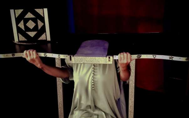 Silhouette en robe pâle suspendue à une barre devant un fond noir, salle L'illusionniste chez TooLate Bayonne