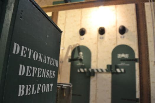 Panneau vert Détonateur défenses Belfort devant des casiers à trous, salle 1916 chez La Clé du Bastion à Belfort