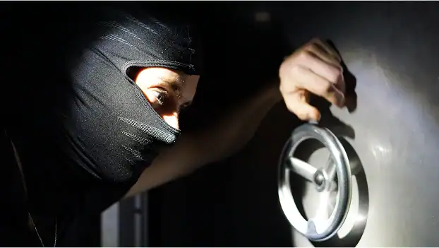 Braqueur masqué manipulant une serrure de coffre-fort dans l'obscurité