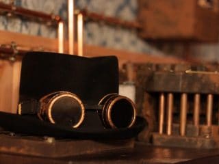 Chapeau haut de forme et lunettes de soudeur de style steampunk sur un établi, salle L'échoppe de madame Ming à Annecy