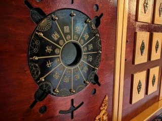 Cadran chinois en métal gravé sur une porte rouge à cadres dorés, salle L'échoppe de madame Ming à Annecy
