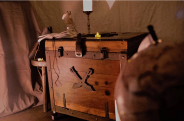 Malle de pirate fermée, bougie et globe au premier plan, La Malle du Capitaine