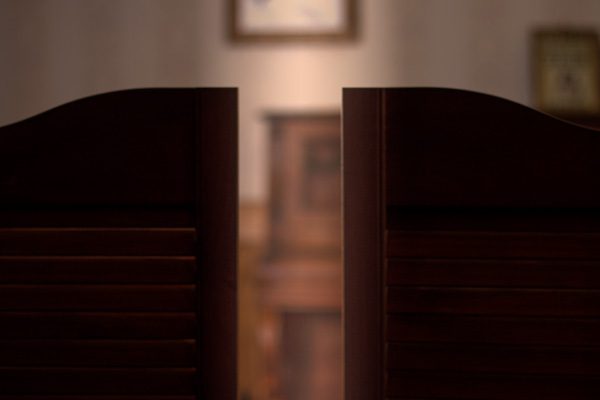 Deux portes en bois sombre entrouverte, intérieur chaleureux de la salle Le trésor perdu