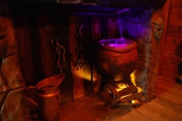 Décor sombre aux teintes orangées et violettes, objets rituels et statuettes dans Magie noire au Défi des Ducs