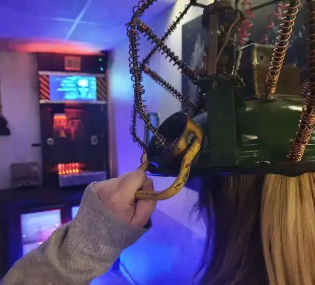 Main tenant un anneau de chaîne devant un appareil à écrans lumineux, salle Les fabuleuses inventions du docteur Apfelglück