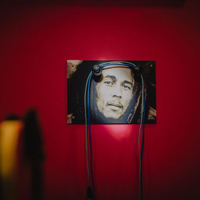 Portrait photo d'un musicien encadré sur un mur rouge, salle Le studio chez Leave in time à Paris