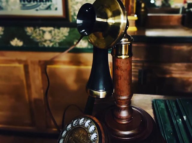 Téléphone chandelier ancien à cadran sur un bureau de bois, salle Gang of Birmingham chez Tempus à Bayonne