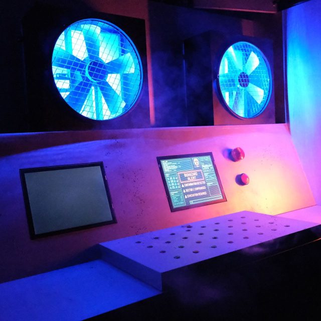 Poste de commande lumineux avec deux grands ventilateurs bleus, salle Le virus chez Rashomon Escape à Paris