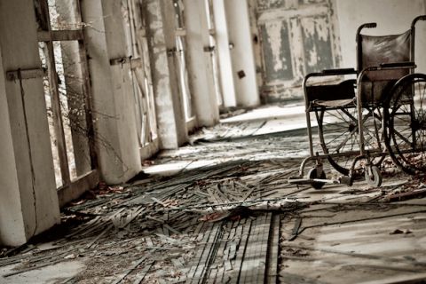 Couloir délabré d'asile avec fauteuil roulant abandonné et murs décrépit