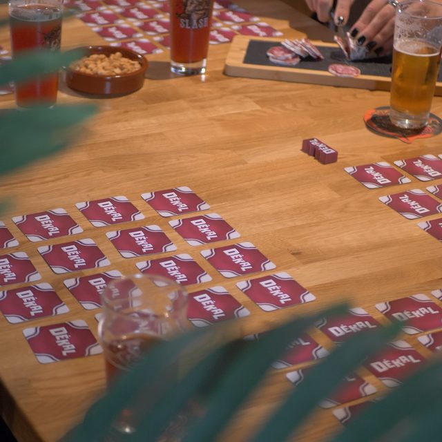 Joueurs autour d'une table en bois avec cartes rouges, verres et collations chez Break Out à Sévrier