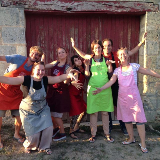 Groupe de joueurs souriants devant une porte rouge en pierre, chez Escape Game Oeno-Logic Blaye