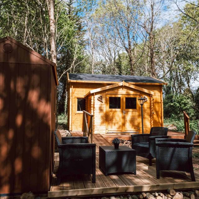 Cabane de bois claire et salon de jardin sur une terrasse en sous-bois, salle Cabane Yavana chez L'Escale des Elfes à Saint-Évarzec