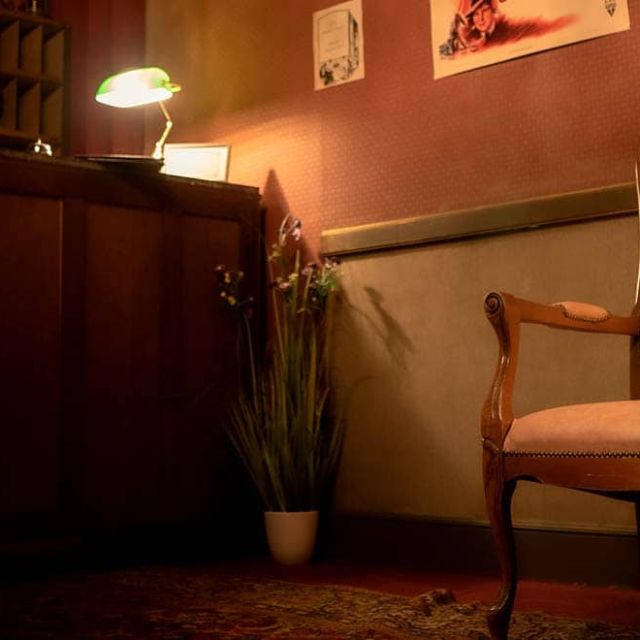 Fauteuil rose clair devant un comptoir de réception et une lampe, salle Sunhill Hotel chez Escape Time à Laval
