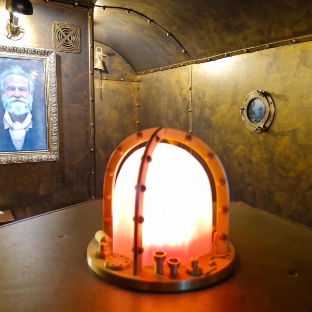 Cabine dorée de style Nautilus avec portrait d'un homme barbu, hublot et lampe orange, salle Sur les traces du magicien