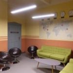 Salle d'attente avec canapé vert, fauteuils noirs et murs bicolores chez Illuminati Escape à Berlin