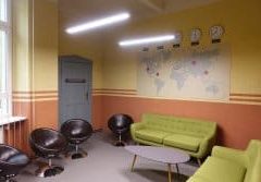 Salle d'attente avec canapé vert, fauteuils noirs et murs bicolores chez Illuminati Escape à Berlin