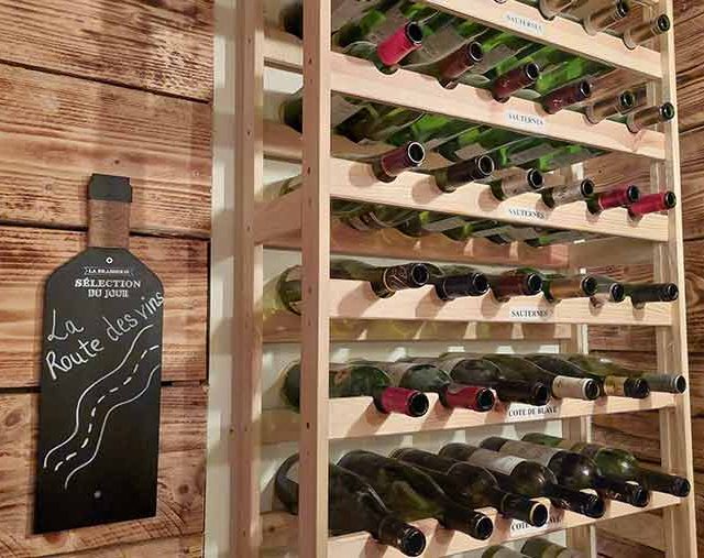 Casiers de rangement en bois clair avec bouteilles de vin et panneau ardoise thème viticulture