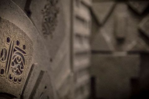 Dalles de pierre gravées de symboles sur un mur gris, tons sépia, salle Projet Omega chez Escape Time à Saint-Herblain