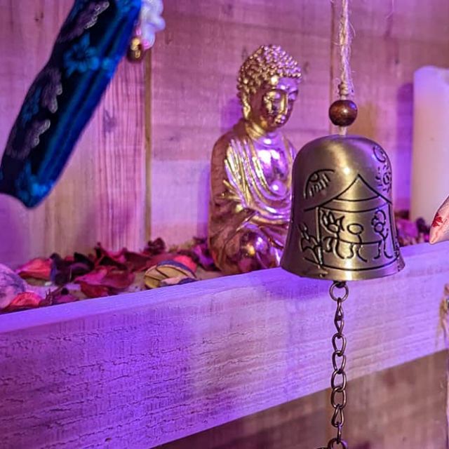 Cloches en bronze, statuette de Bouddha et objets sur une étagère sous lumière violette, salle Mission Tokyo à Angers
