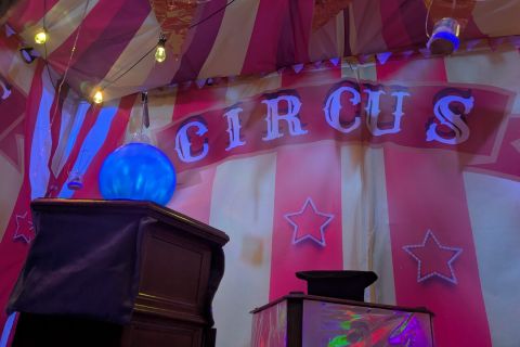 Entrée de chapiteau rayé rouge et blanc avec lettres Circus et boule bleue, salle Circus chez Prisme Escape Game