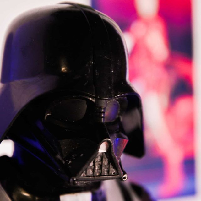 Figurine Darth Vader éclairée en bleu et rose, décor futuriste flou en arrière-plan