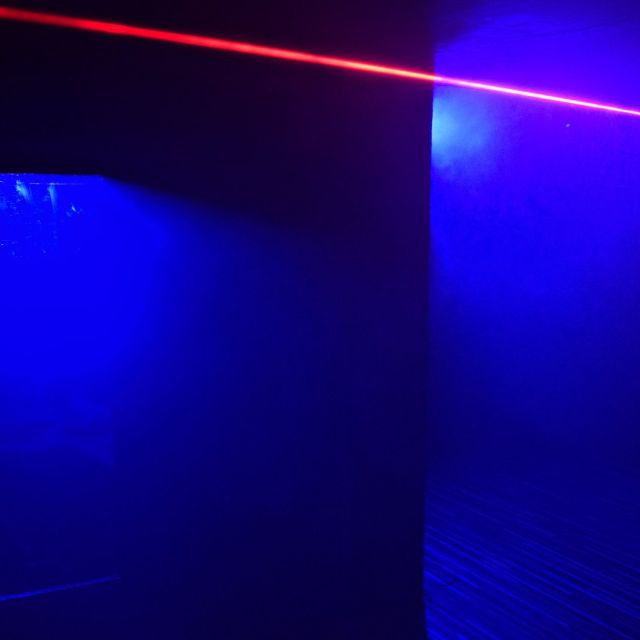 Faisceau laser rouge traversant une pièce éclairée de bleu, salle La reine rouge chez Wood Escape à Locquignol