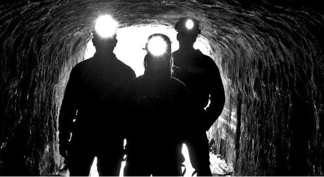 Trois joueurs avec lampes frontales dans un tunnel de mine sombre