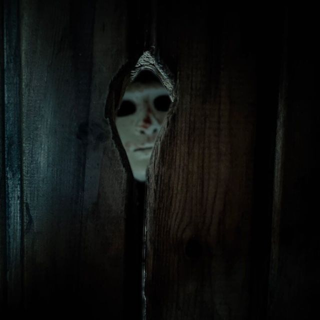 Créature au visage blafard dans un couloir sombre, décor carcéral de la salle Enterrés vivants