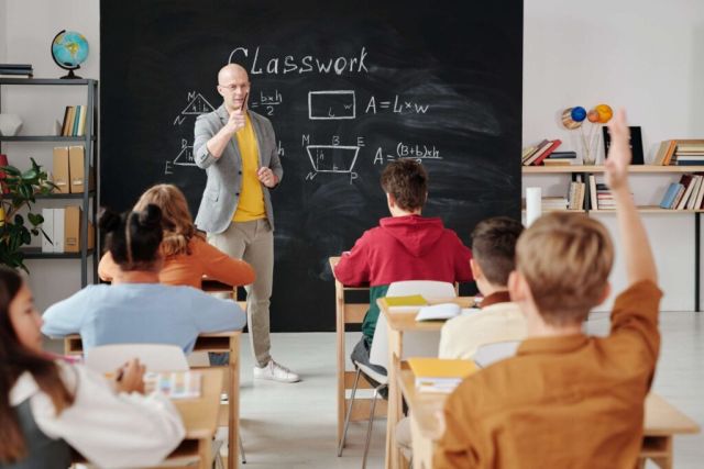 Un professeur enseigne des formules mathématiques à des enfants assis dans une salle de classe