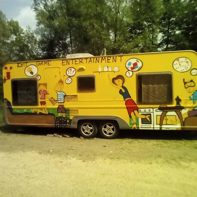 Caravane jaune ornée de dessins de personnages, garée sous les arbres, salle Néo trouv'tout chez La Cabale à Coubon