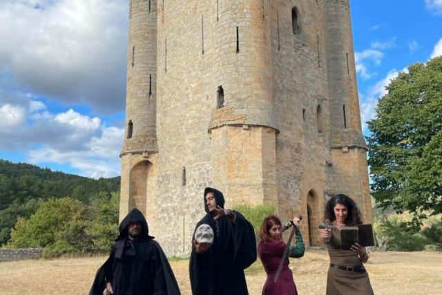Quatre visiteurs en costumes médiévaux devant la Tour de Guet à Arques