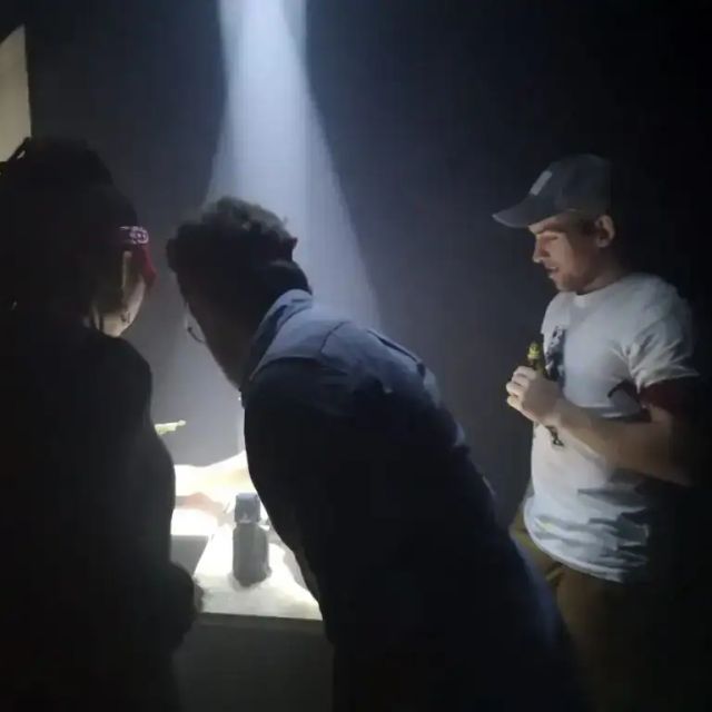 Trois joueurs autour d'une table éclairée par un faisceau, salle Le Tour du monde chez Puzzle animations à Grenoble