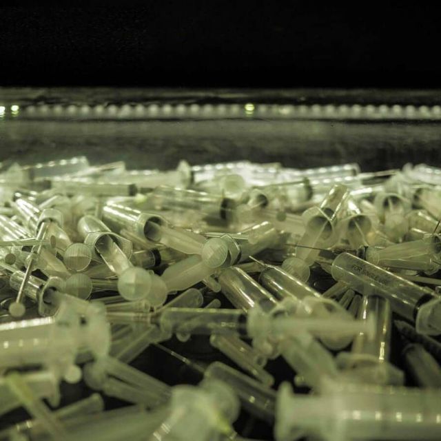 Seringues et instruments médicaux sous lumière verte dans The Saw Massacre