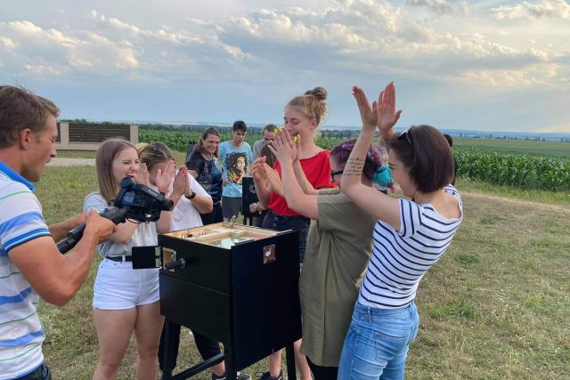 Groupe autour d'une boîte à énigmes en plein air, deux joueuses se tapent dans les mains, Escape Arena