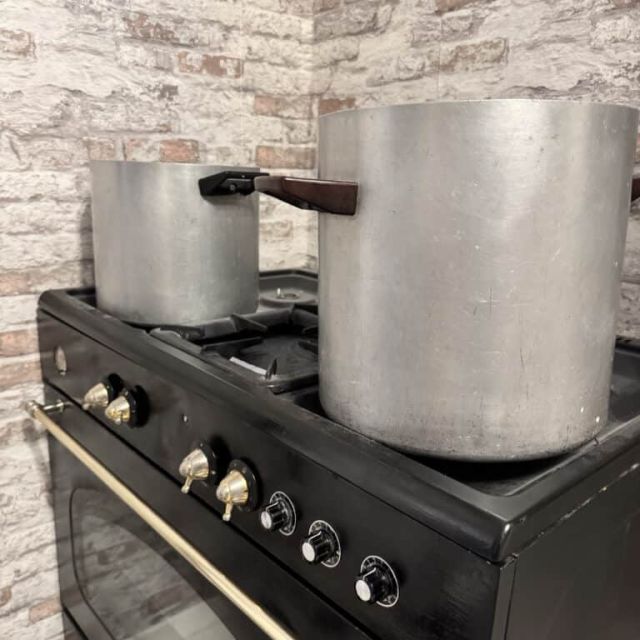 Piano de cuisson noir avec deux grandes marmites en aluminium, salle Le grand restaurant chez Escape Factory à Guérande