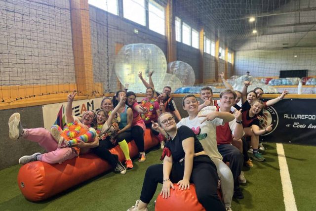 Groupe de joueurs posant dans une salle de jeu avec ballons rouges et filets