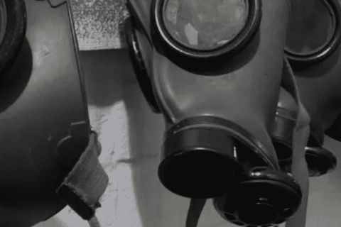 Rangée de masques à gaz noirs en noir et blanc, salle Contamination chez Escape Yourself au Mans