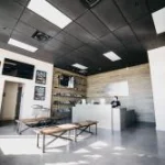 Salle d'escape game aux murs clairs, éclairage néon, mobilier minimaliste et tables de jeu