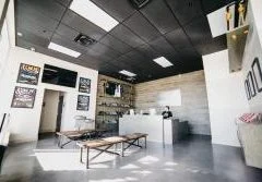 Salle d'escape game aux murs clairs, éclairage néon, mobilier minimaliste et tables de jeu