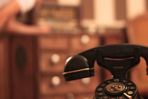 Téléphone à cadran noir sur un meuble de bureau en bois, salle Londres sous haute tension chez Mission Escape à Vedène