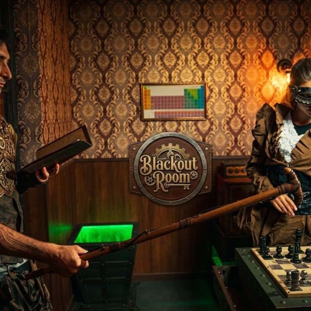 Guerrier en armure et joueur à lunettes autour d'un échiquier, enseigne BlackOut Room au mur, salle Steampunk à Nice