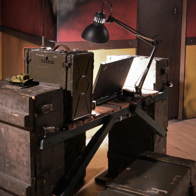 Bunker militaire avec pupitres, malles, lampe d'interrogatoire et équipement vintage, chez Team Break Terville